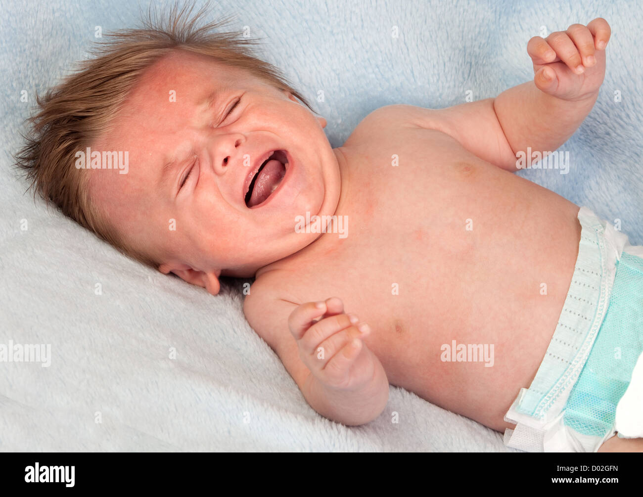 Beautiful blond baby crying on blue blanket Stock Photo