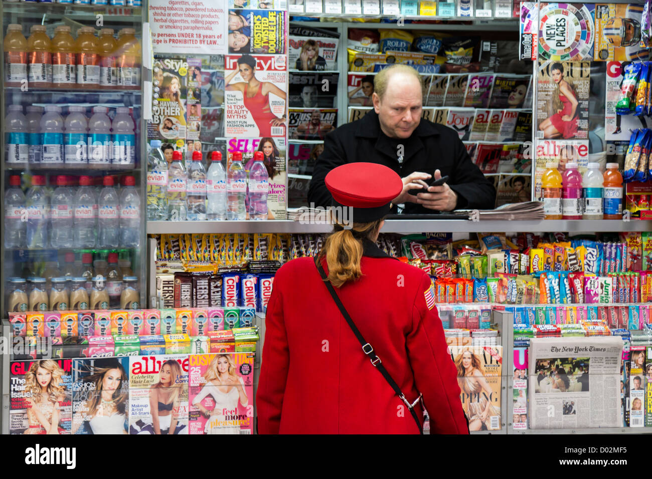 Woman in a red uniform in front of a newsstand seller in Wall Street, New York Stock Photo