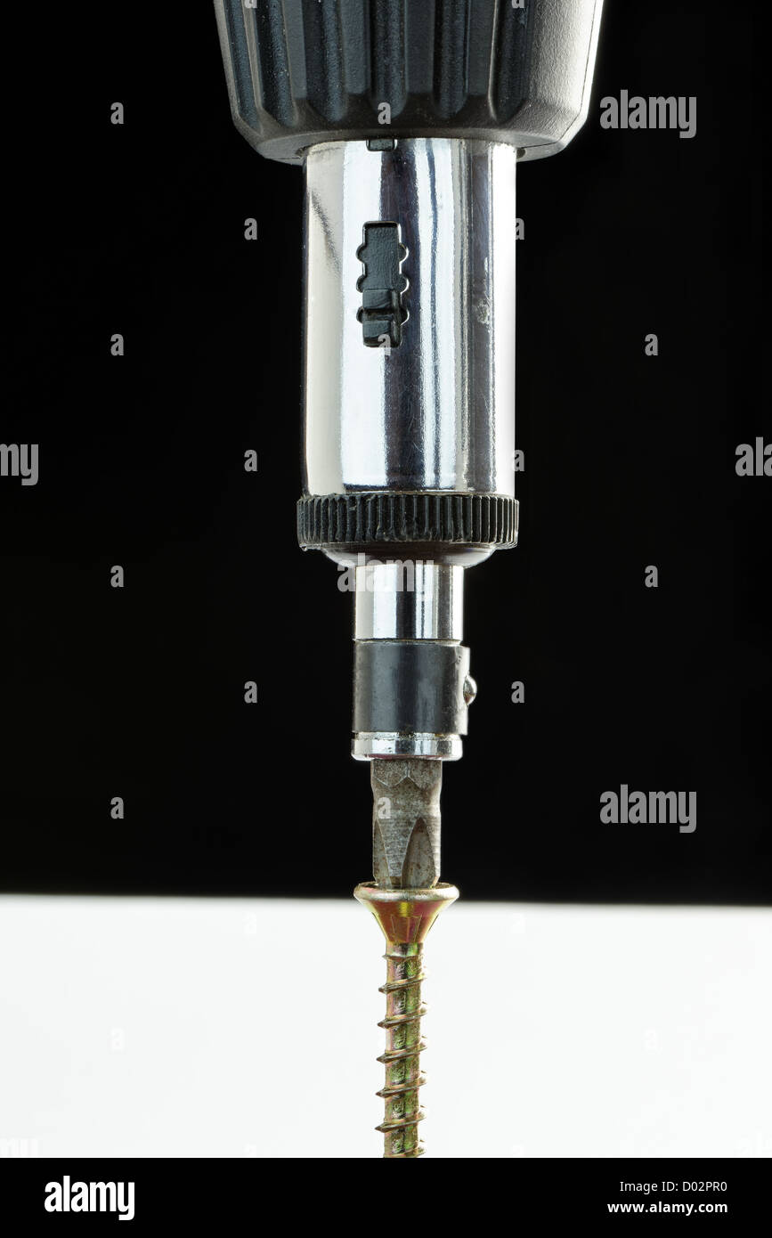 Close-up of a ratchet screwdriver driving a brass screw Stock Photo