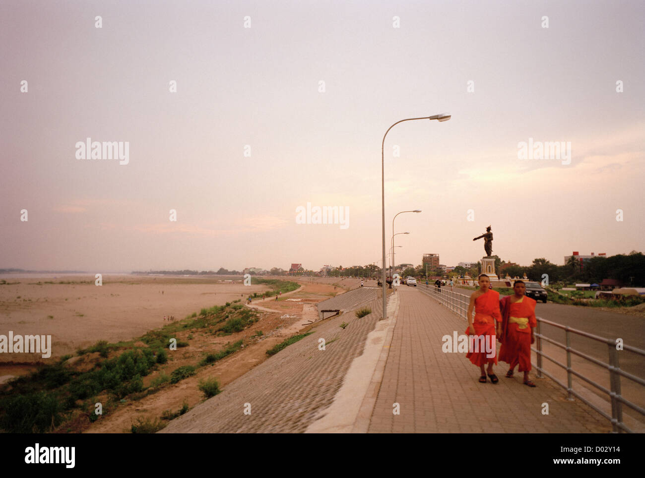 Two young Buddhist monks walk on the banks of the Mekong river in Vientiane in Laos in Indochina in Far East Southeast Asia. Religion People Buddhism Stock Photo