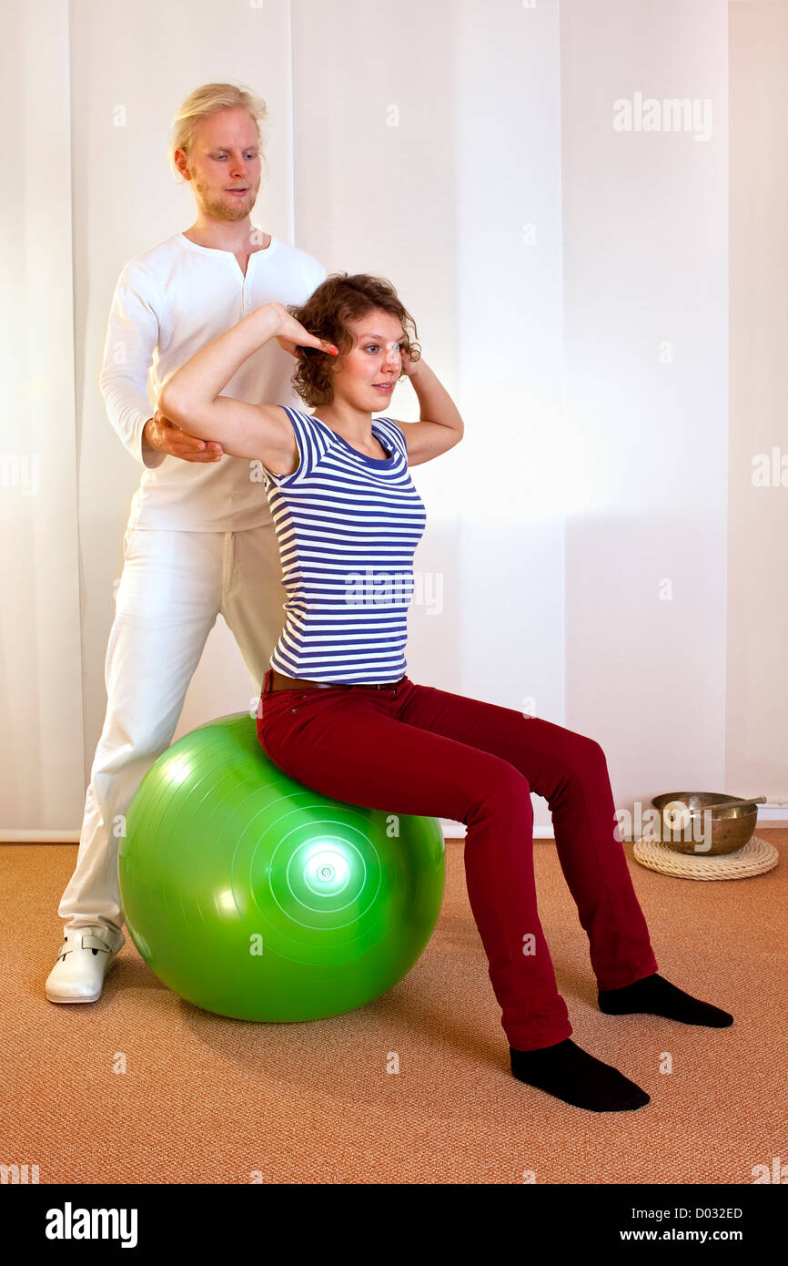 adult practicing poses on exercise ball with professional Stock Photo
