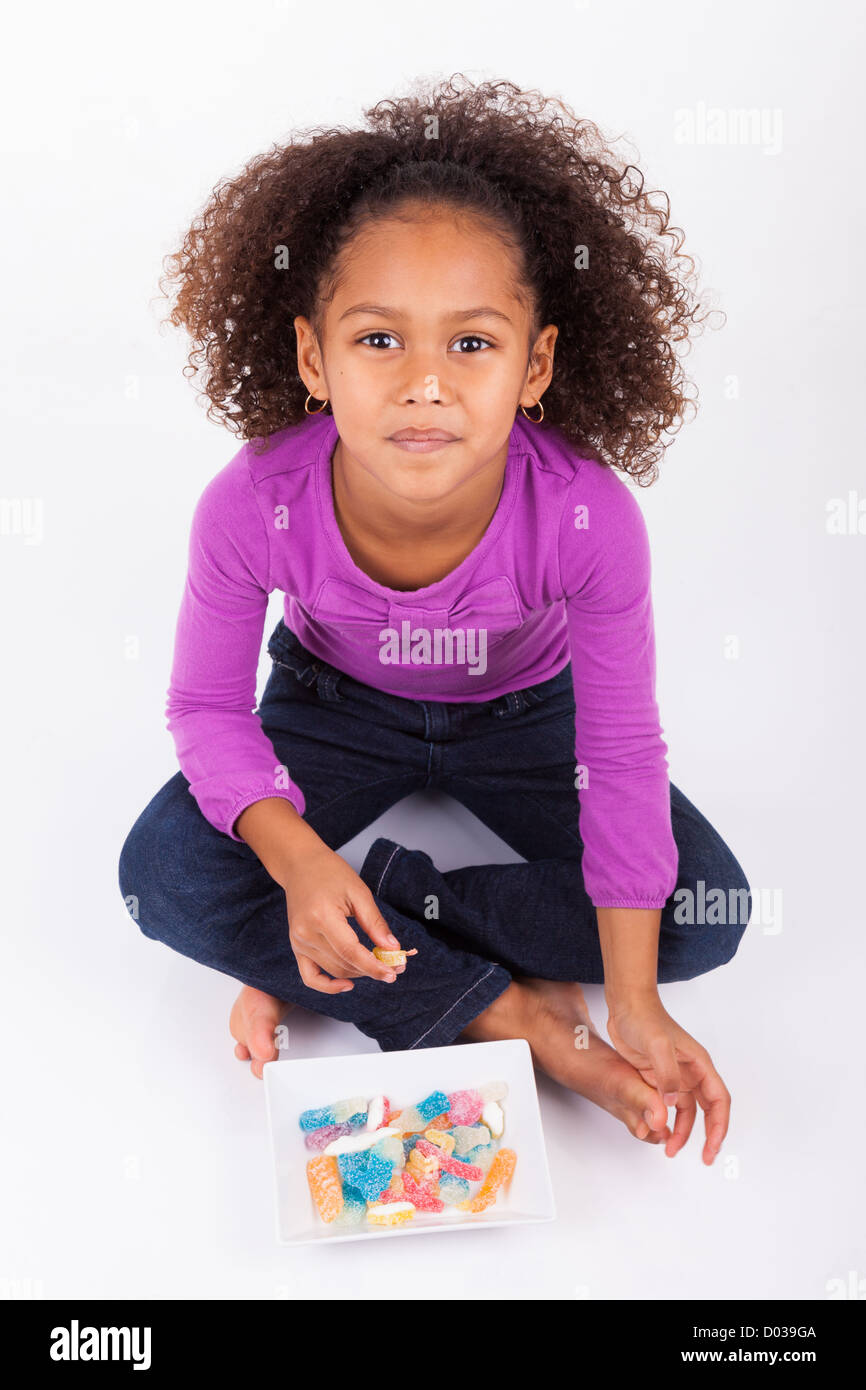 Little African Asian girl eating candy, isolated on white background ...