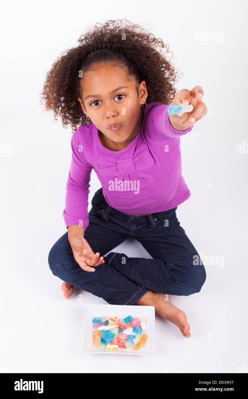 Little African Asian girl eating candy, isolated on white background ...