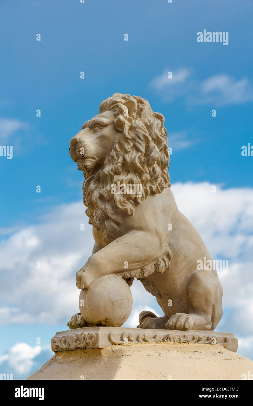 Statue of a lion with ball against a blue sky Stock Photo