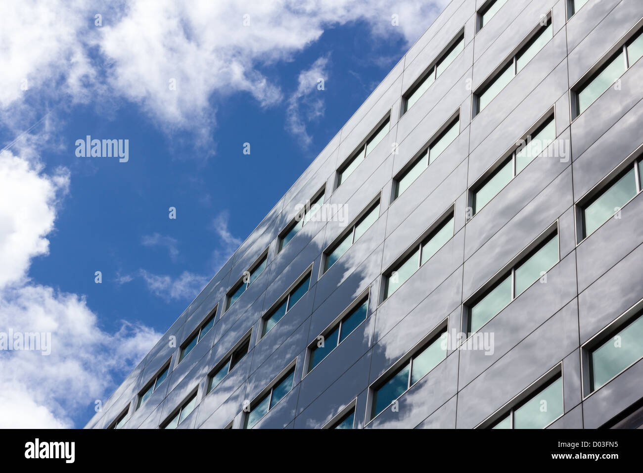 Office building with green tinted windows reflects the cloudy sky Stock Photo