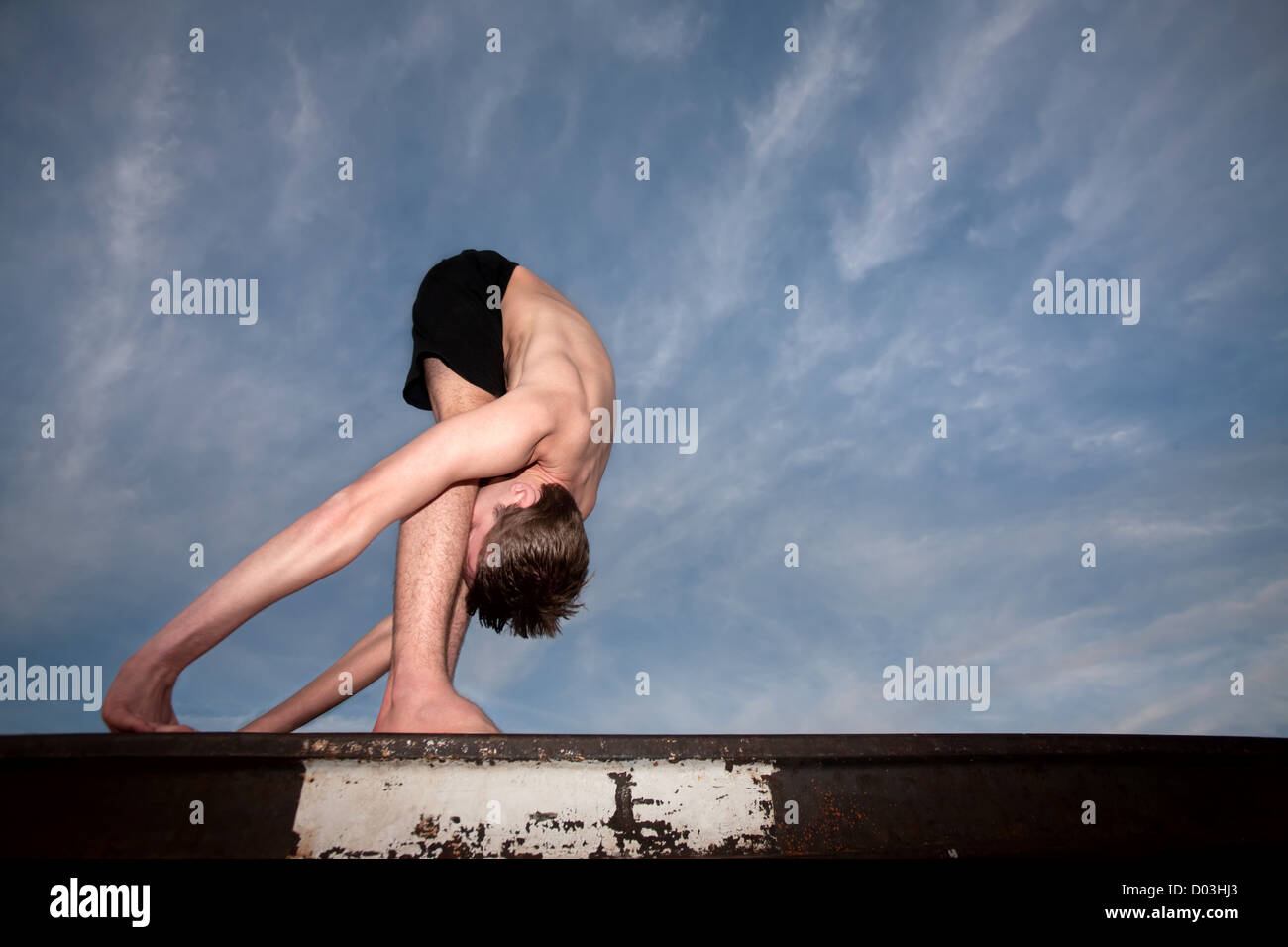 Extremely flexible yoga practitioner outside on rail track Stock Photo