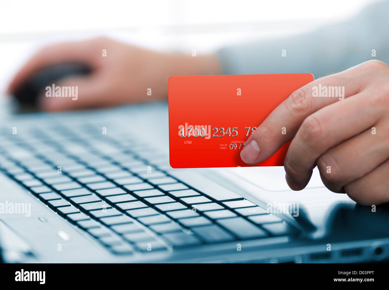 Man holding credit card in hand and entering security code using laptop