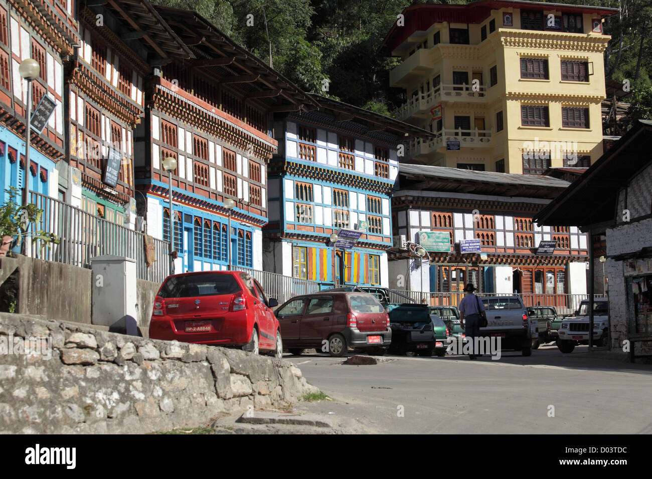 A street in Bhutan where cars are parked and the shops and local hotels