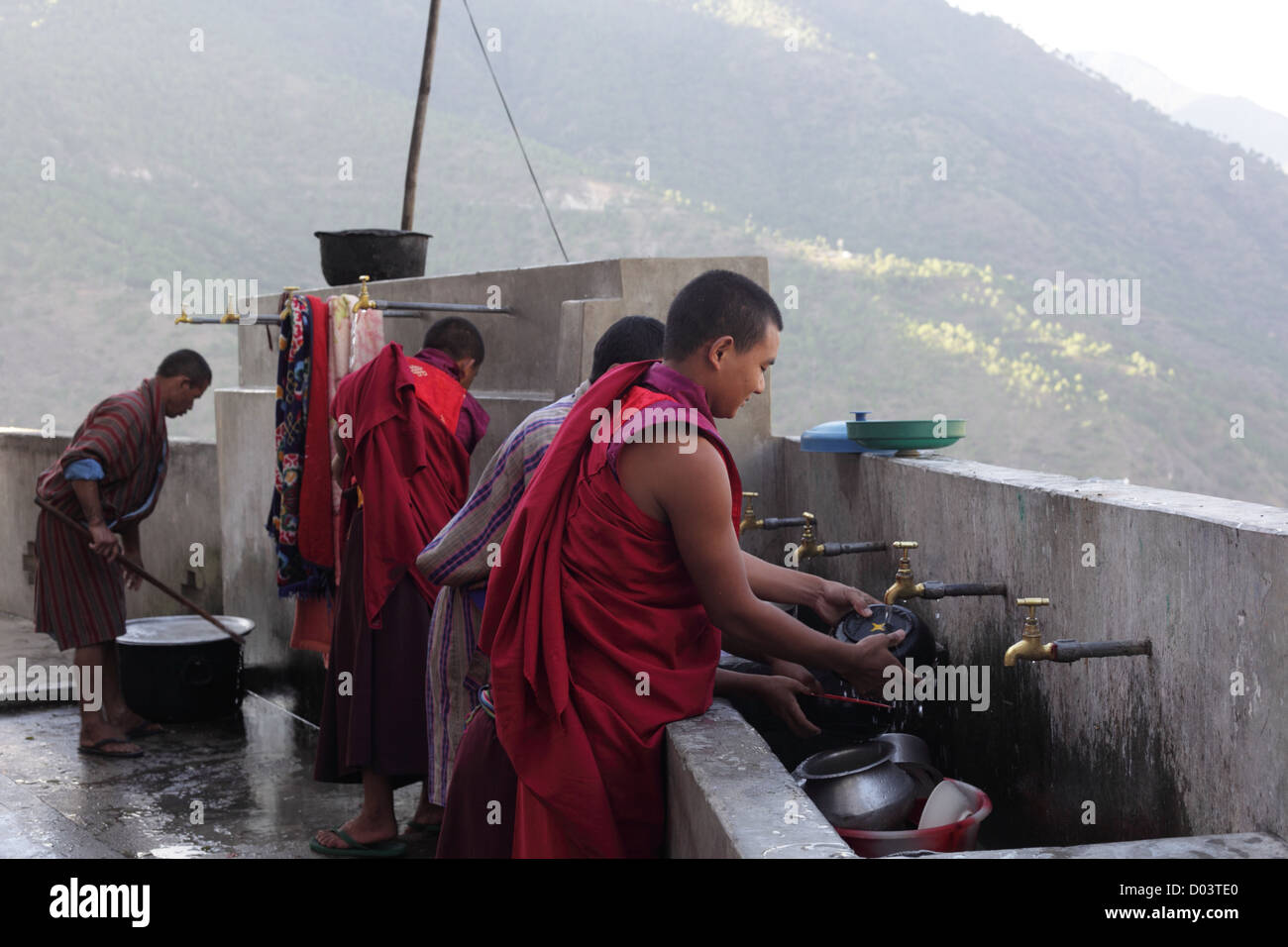 Bhutanese Buddhist monks clean the dishes of the monastery after a meal at a temple in Bhutan. Stock Photo