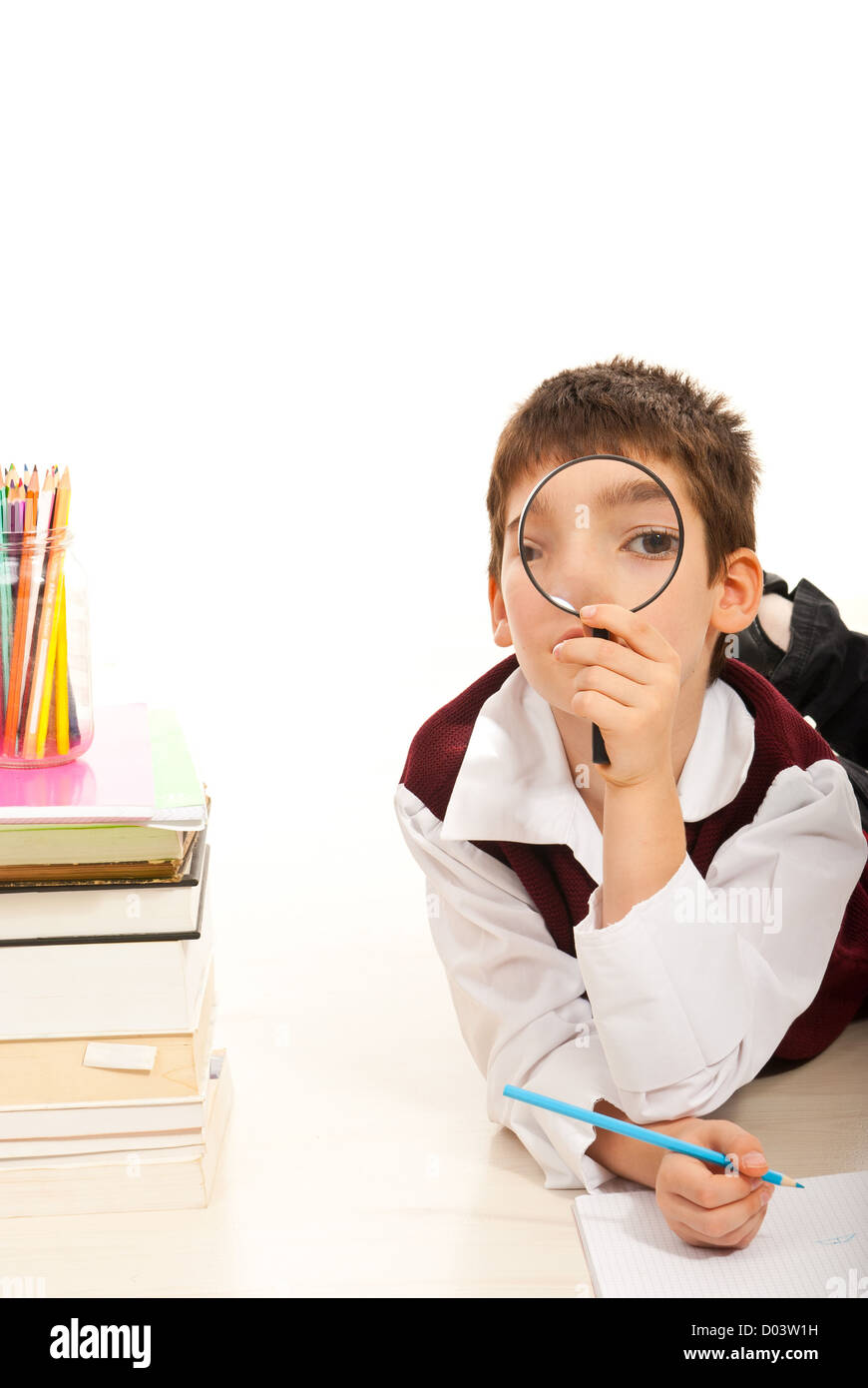 School boy looking through loupe and doing homework Stock Photo - Alamy