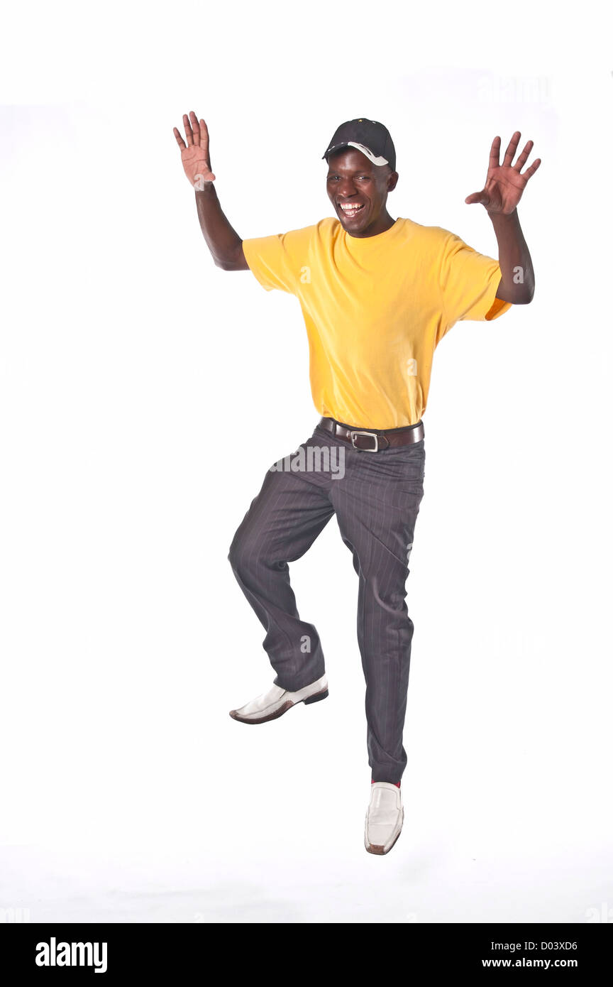 Man in yellow top and jeans jumping with arms raised Stock Photo