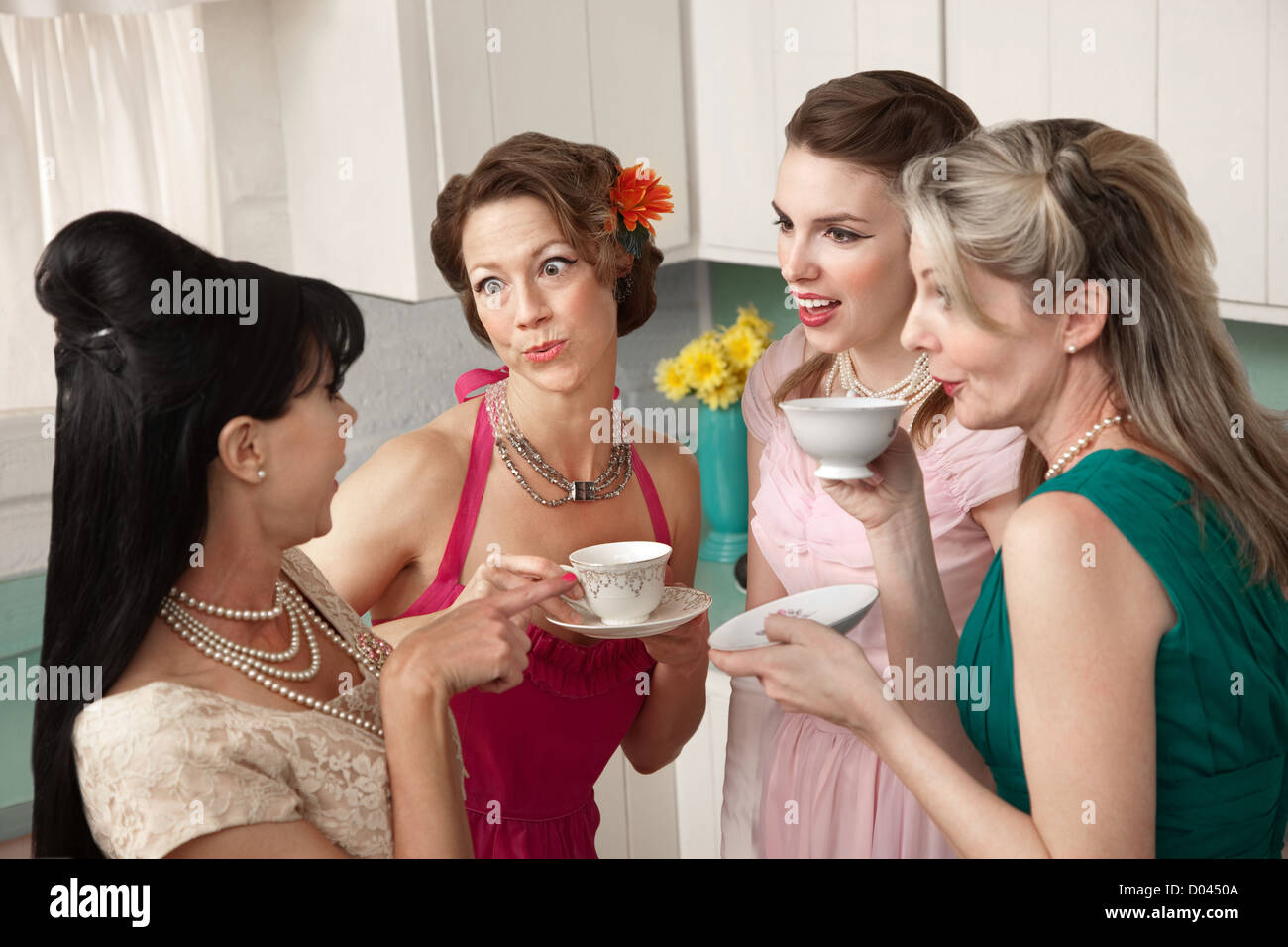 Four retro-styled women chit-chat over coffee in a kitchen Stock Photo