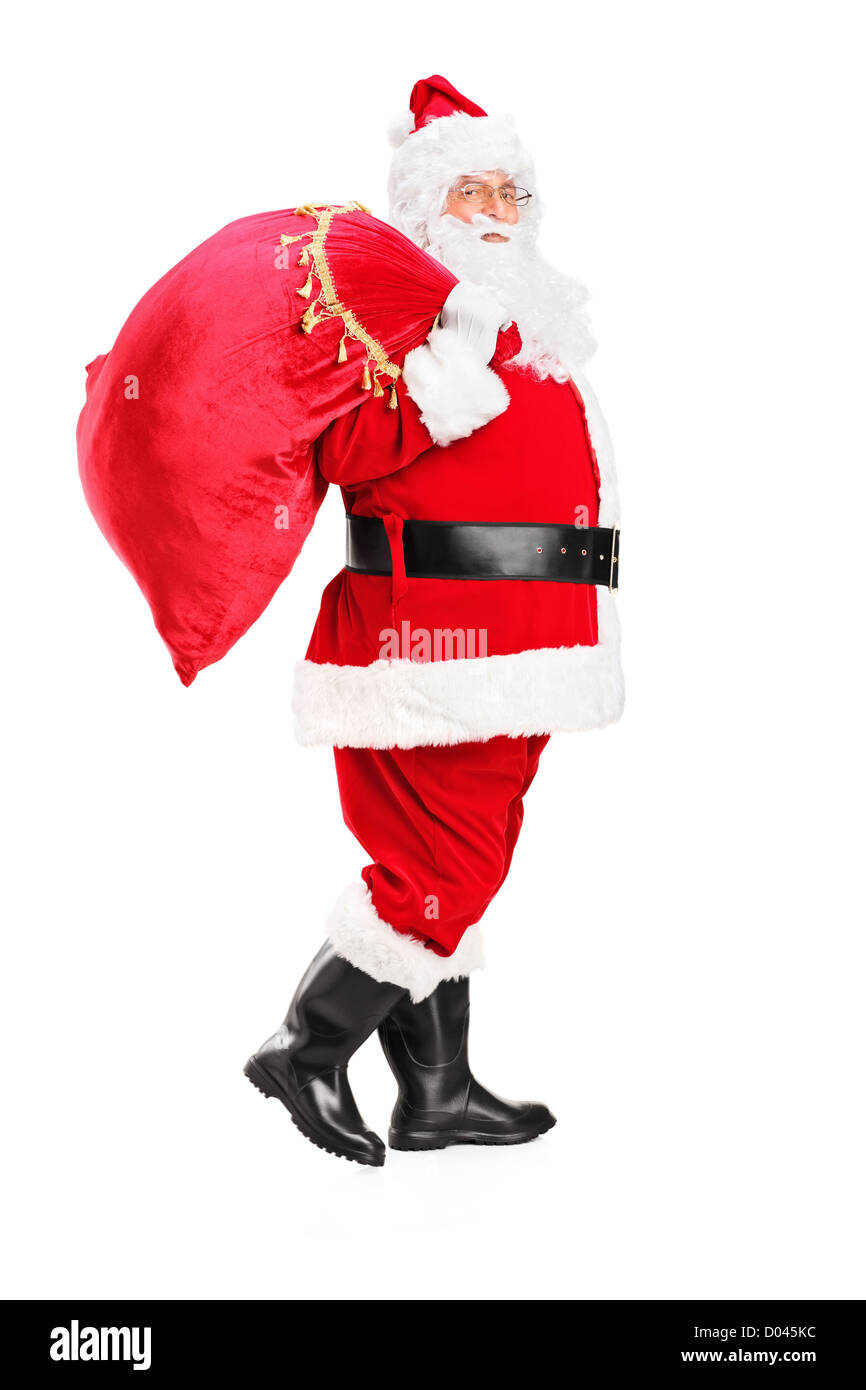 Full length portrait of a Santa Claus walking with bag full of gifts og his back isolated on white background Stock Photo