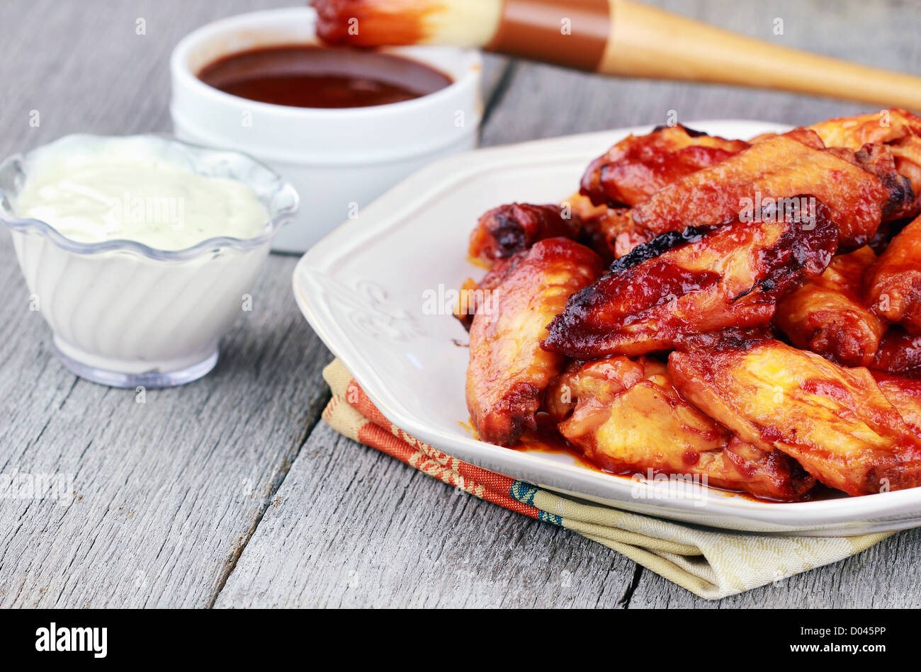 Plate of chicken wings Ranch dressing and BBQ sauce with basting brush