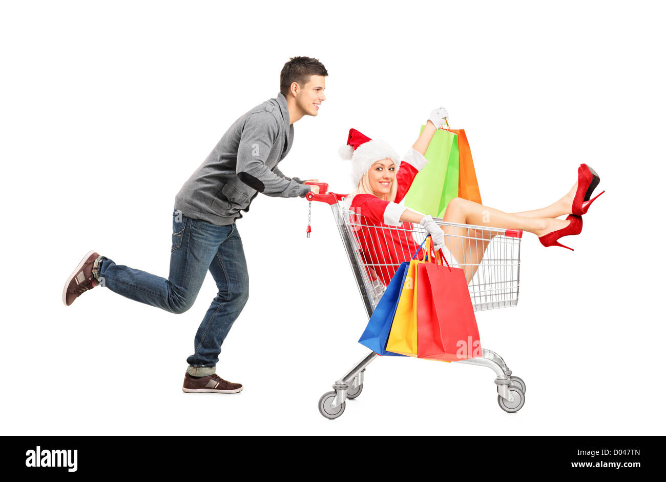 Happy guy pushing a female wearing christmas costume in a shopping cart isolated on white Stock Photo
