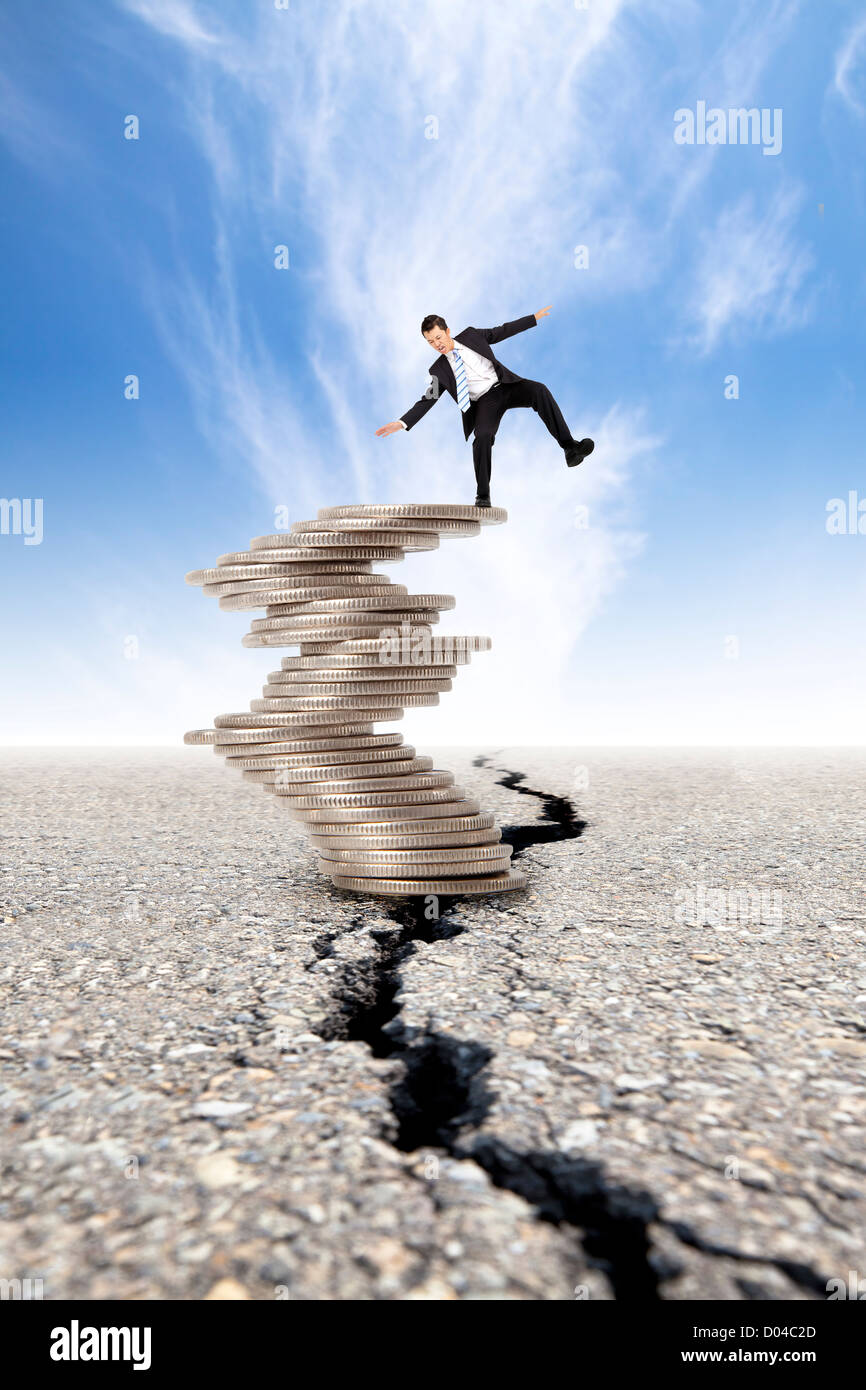 busines and Economic crisis concept cracked road and unstable businessman on the money tower Stock Photo