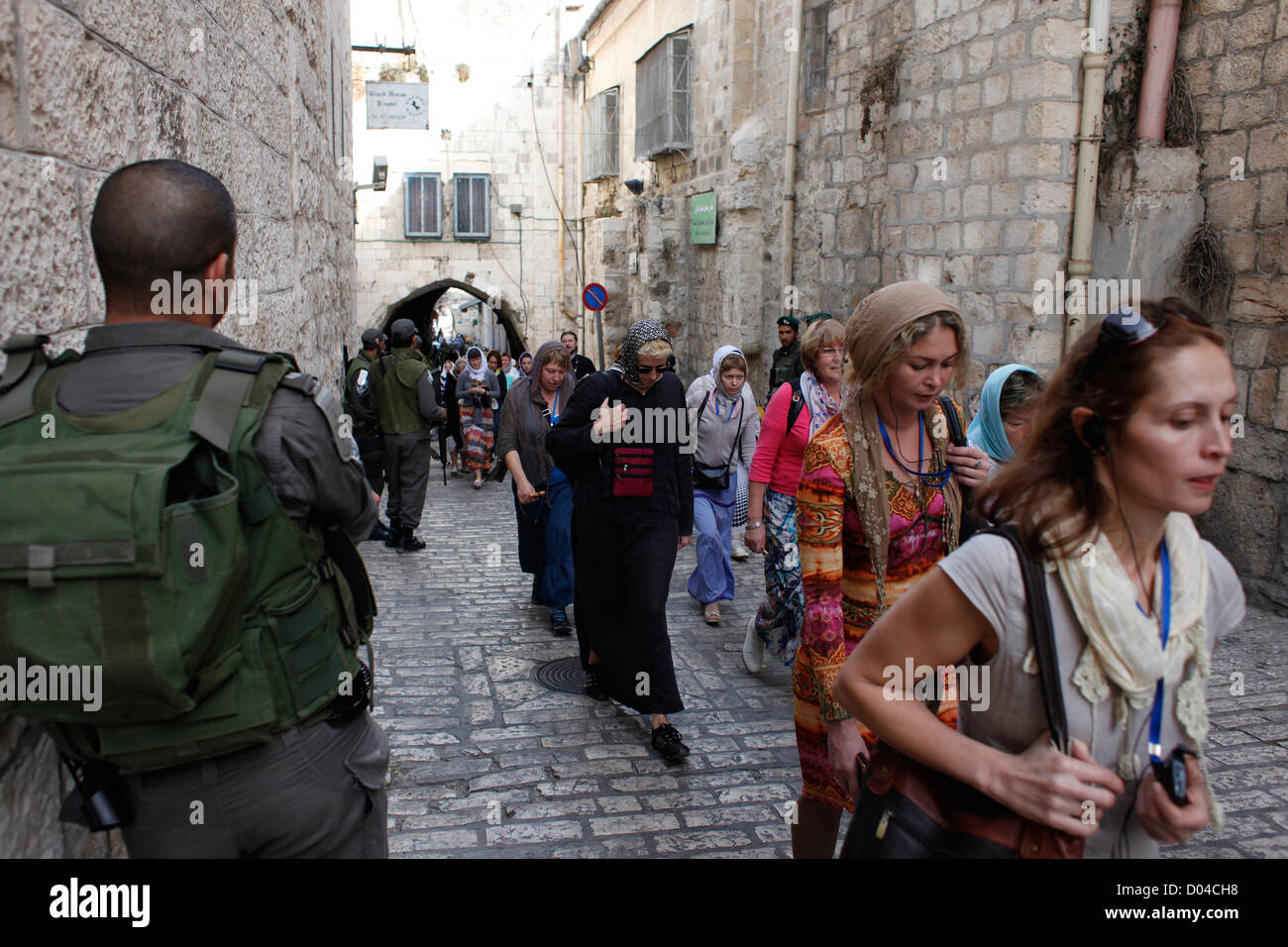 Israeli soldiers stand guard as a group of Christian pilgrims walk along Via Dolorosa street believed to be the path that Jesus walked on the way to his crucifixion in the Old City. East Jerusalem, Israel Stock Photo