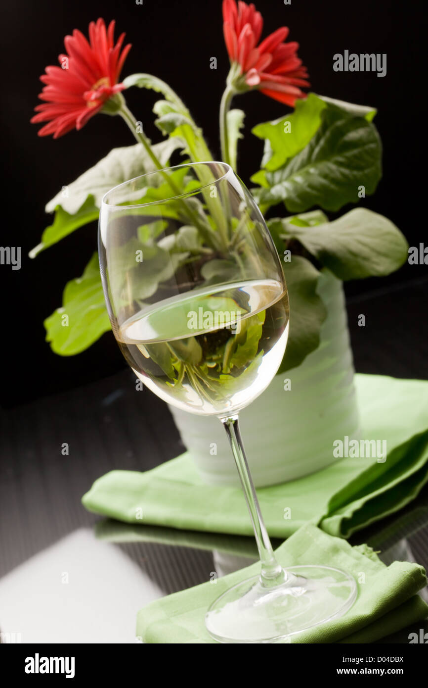 photo of calyx with white wine and red flower in the background Stock Photo