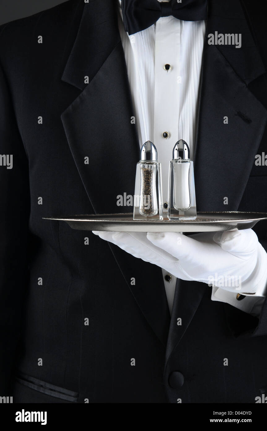 Closeup of a Waiter wearing a tuxedo holding a serving tray with salt and pepper shakers. Stock Photo