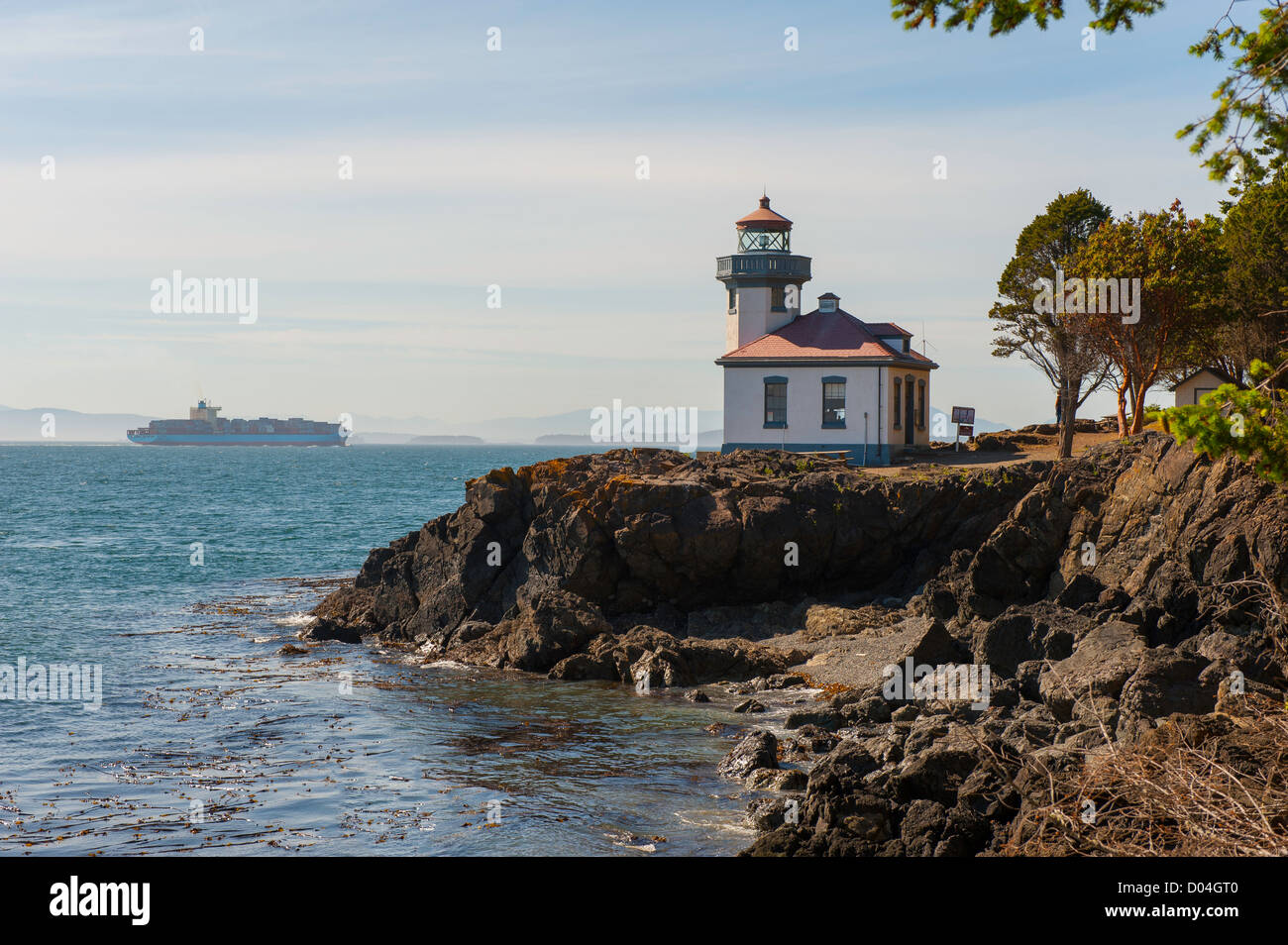A freighter passes Lime Kiln Lighthouse during a sunny spring day. Stock Photo