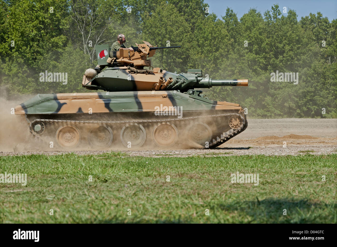 A camouflaged US Army M551 Sheridan light tank moving at speed over open ground. Sheridans first saw combat in Vietnam in 1969. Stock Photo