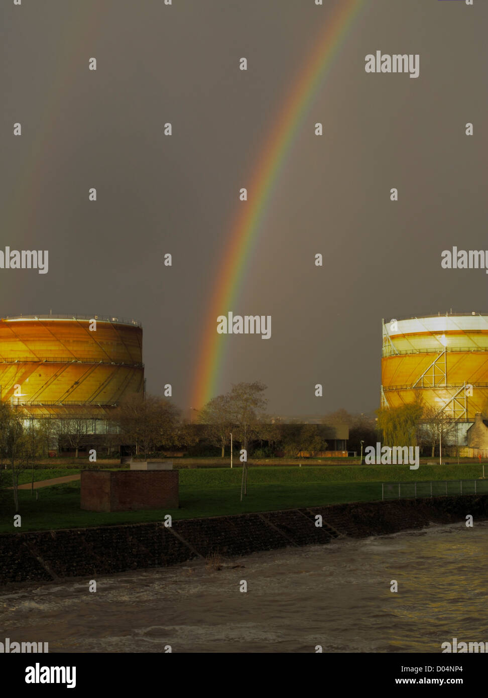 A rainbow against a dark threatening sky between gasometers Exeter canal Devon UK energy prices gasometer Stock Photo
