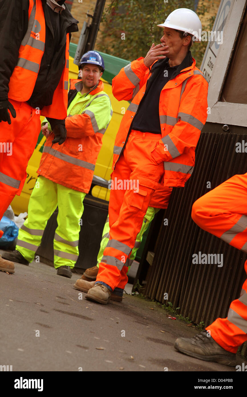 Construction workers taking a cigarette break, in their orange safety wear, London, 8th November 2012 Stock Photo