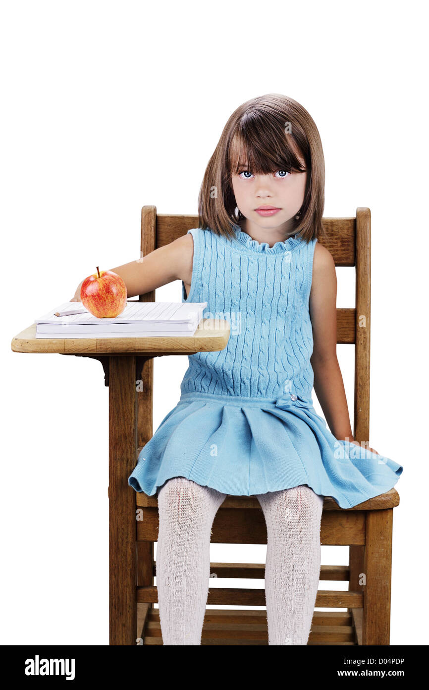 Little girl sitting at a school desk with apple and books Isolated on a ...