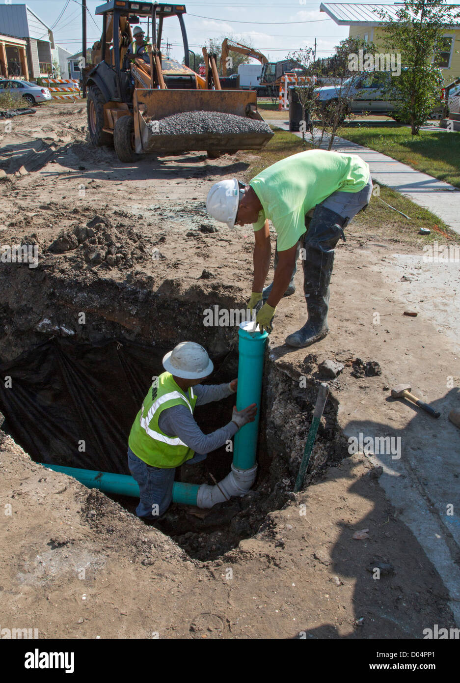 Seven years after Hurricane Katrina, workers hook up a sewer line to a new home in New Orleans' lower ninth ward. Stock Photo