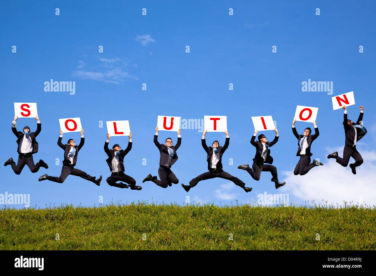happy businessman holding solution text and jumping on the green field