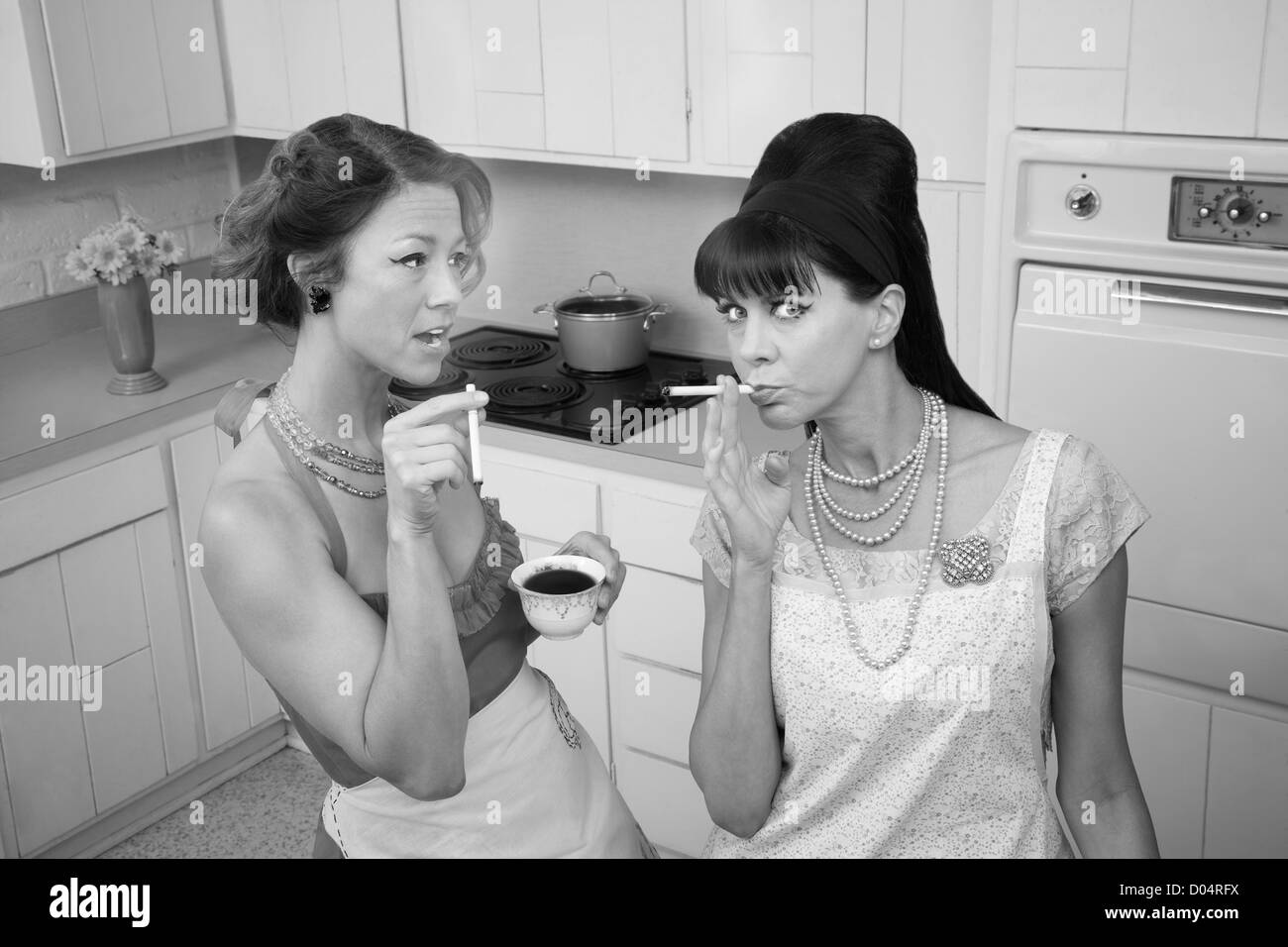 Two middle-aged retro styled women smoking cigarettes and having coffee Stock Photo