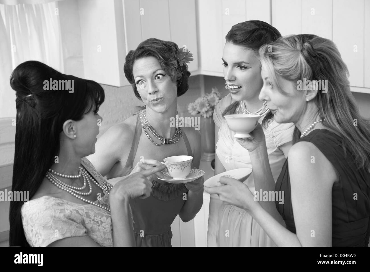 Four retro-styled women chit-chat over coffee in a kitchen Stock Photo