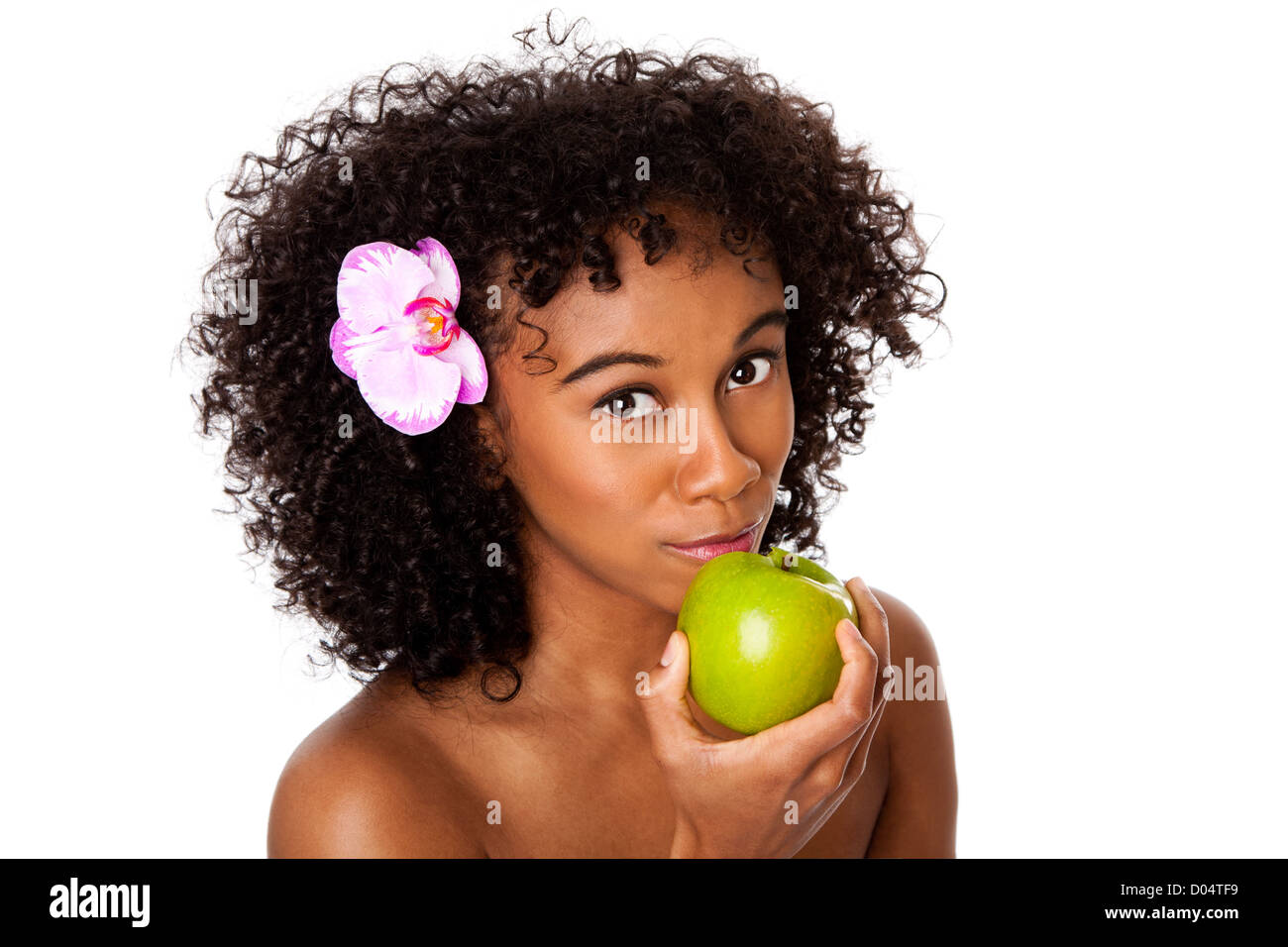 Beautiful happy woman with orchid flower in curly hair eating healthy green apple, isolated. Stock Photo