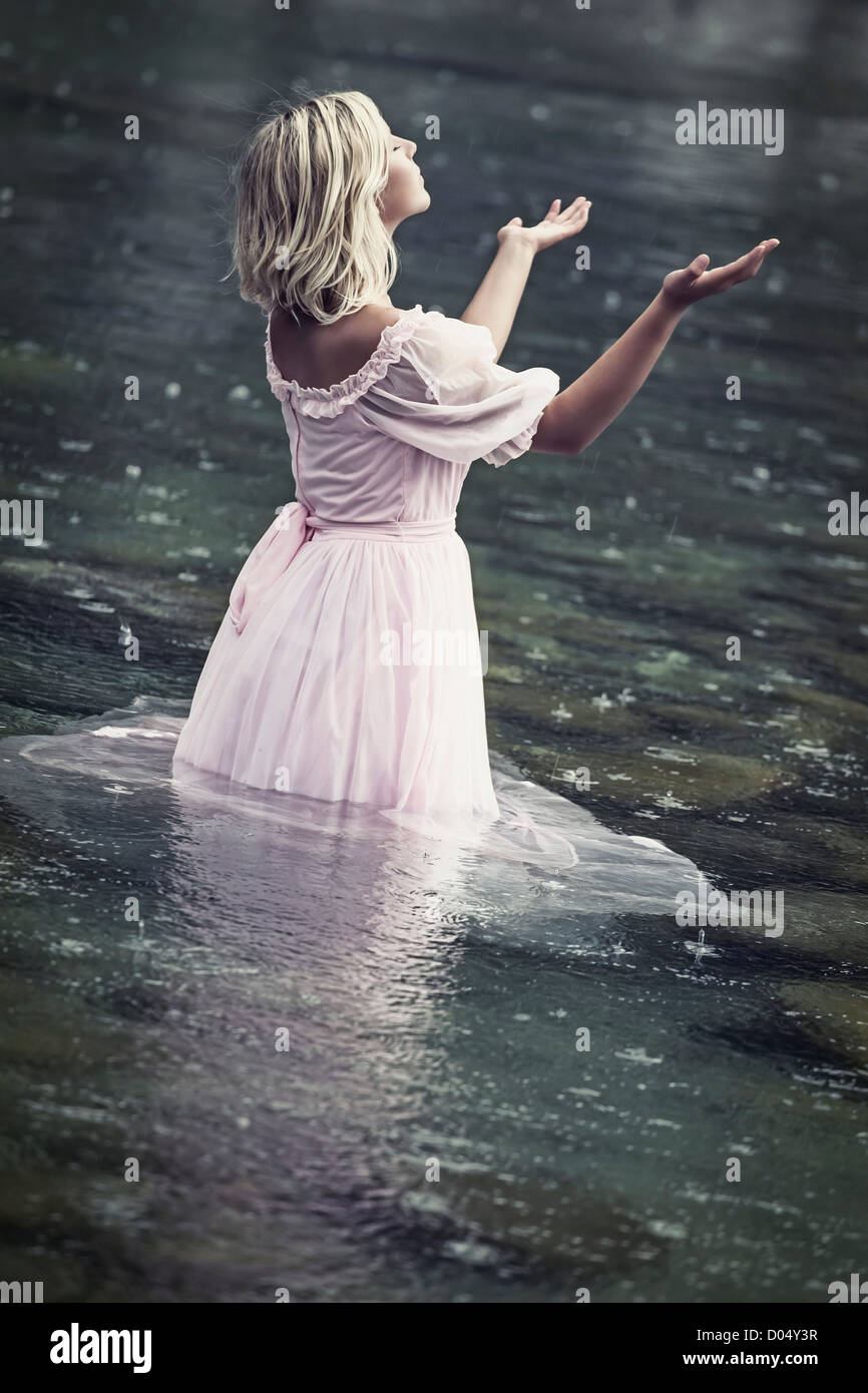 a woman standing in the water and enjoying the rain Stock Photo