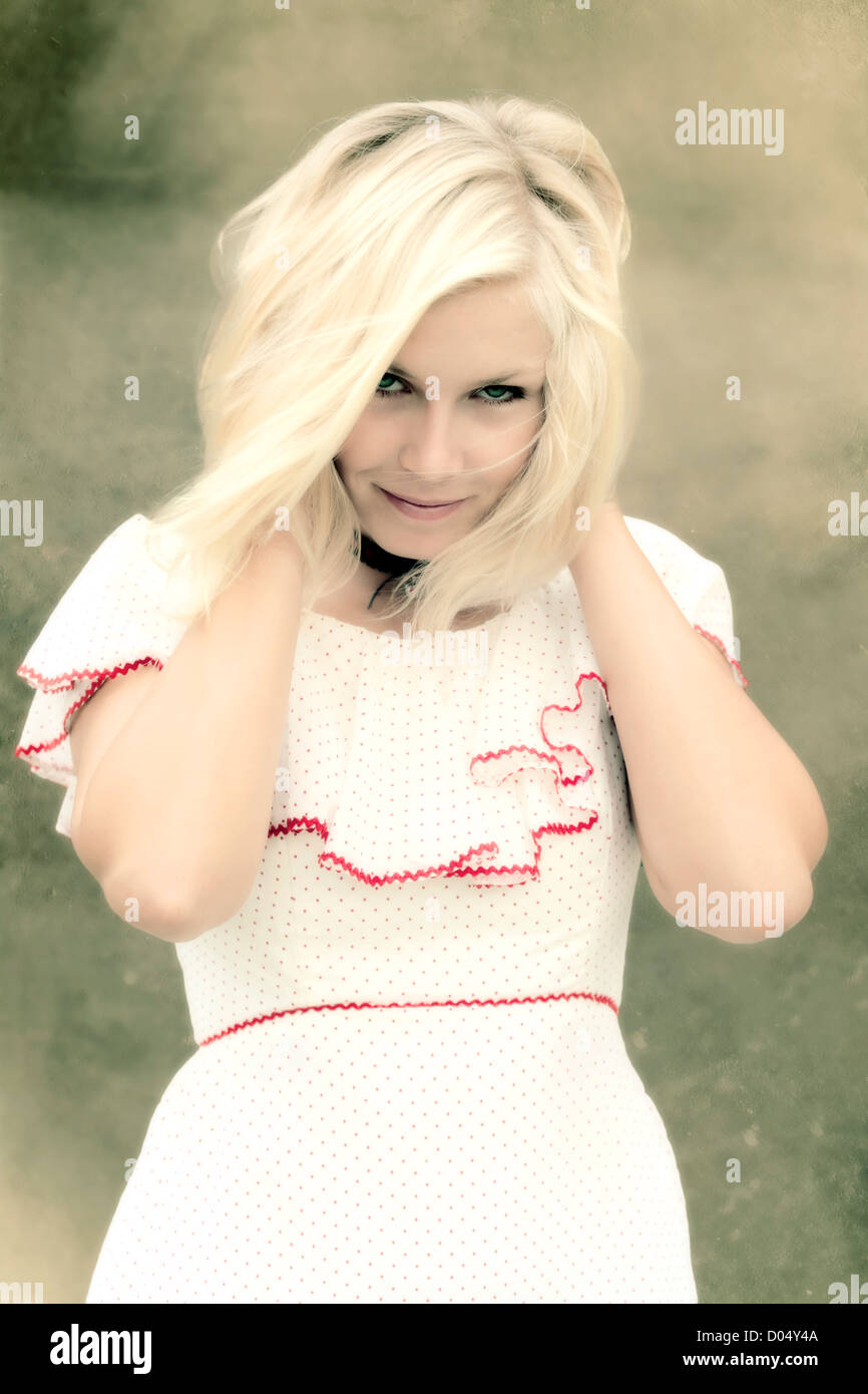 portrait of a beautiful, young, blonde girl in a white dress with red ...