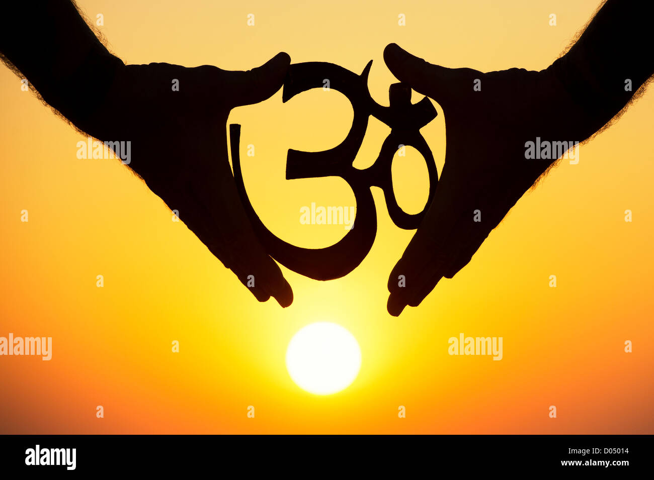Hands holding Hindu OM / AUM symbol at sunset. India. Silhouette Stock Photo