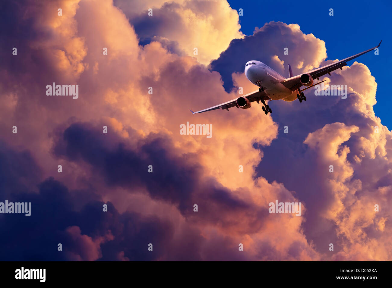 Jet plane is maneuvering for landing in a spectacular sunset sky Stock Photo