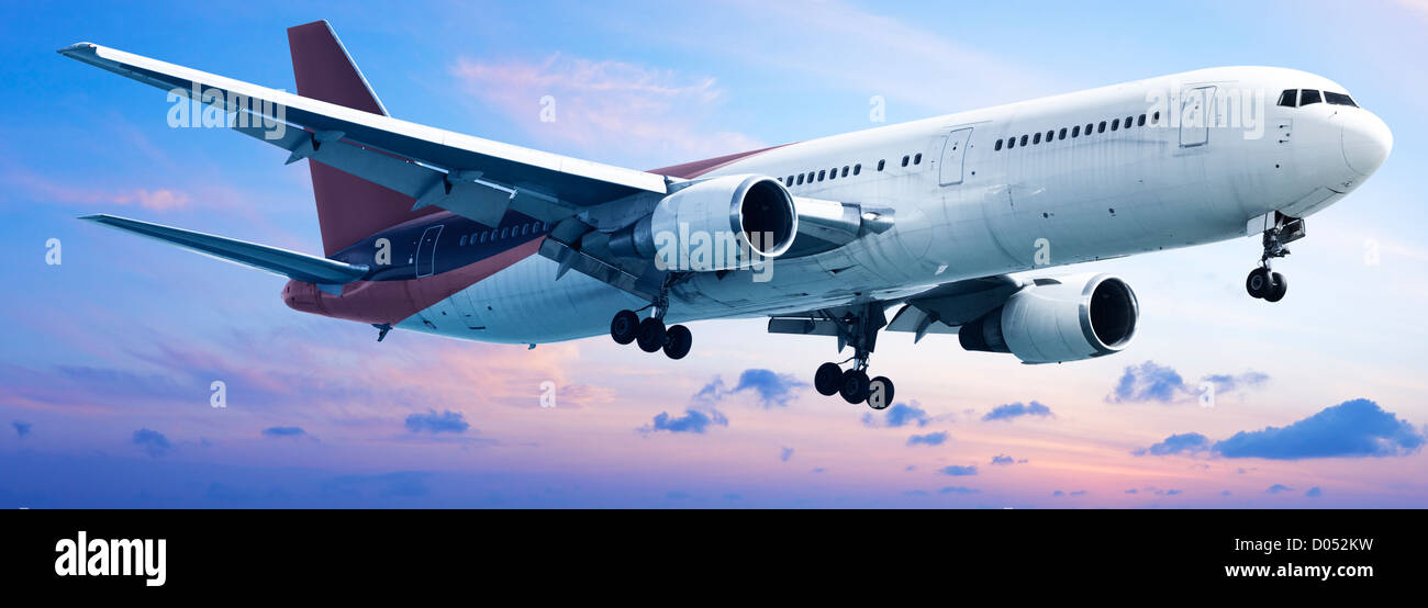Aircraft is maneuvering in a sunset sky. Panoramic composition. Stock Photo