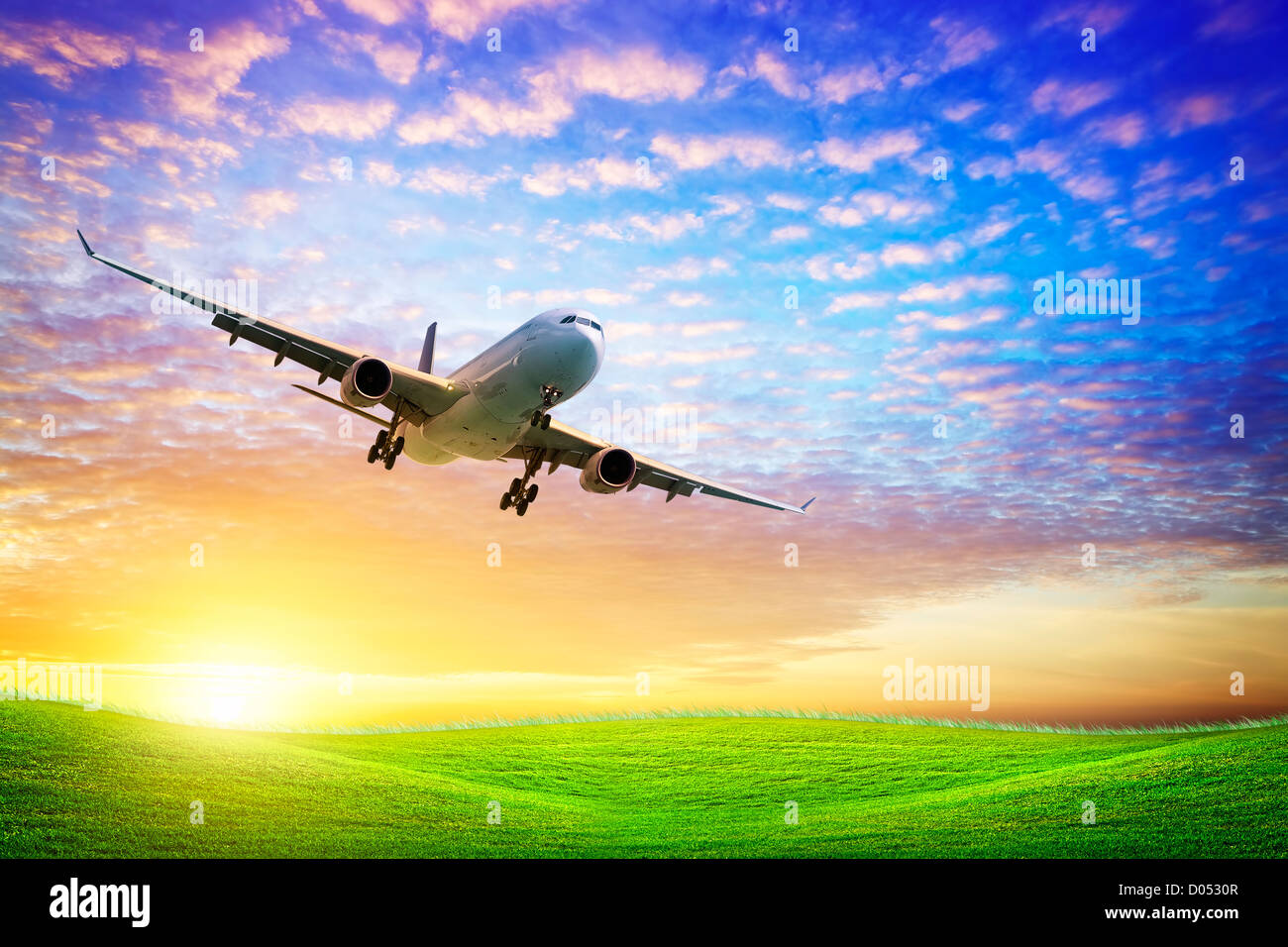 Jet aircraft over the field of green at sunset Stock Photo