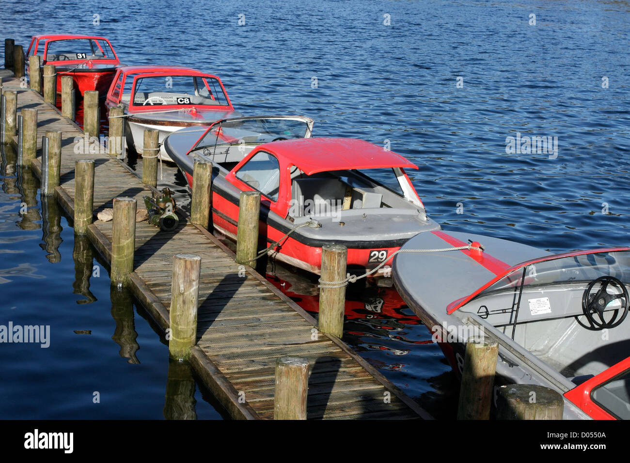 A row of small motor boats (for hire) moored at Bowness on the shores of Lake Windermere, Cumbria, England. Stock Photo