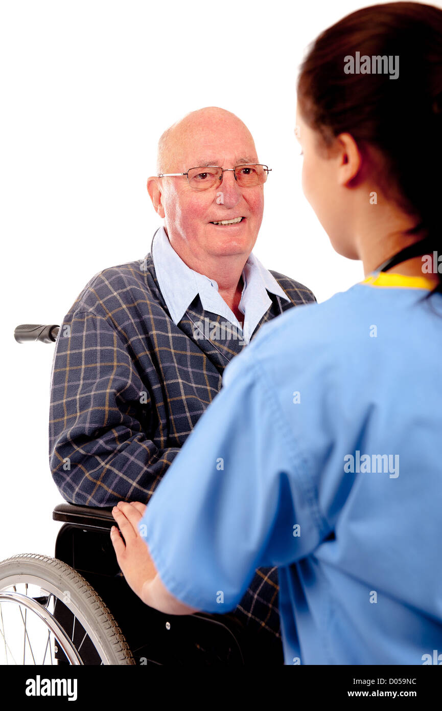 Female nurse attending to elderly male patient sitting in a wheelchair. Stock Photo
