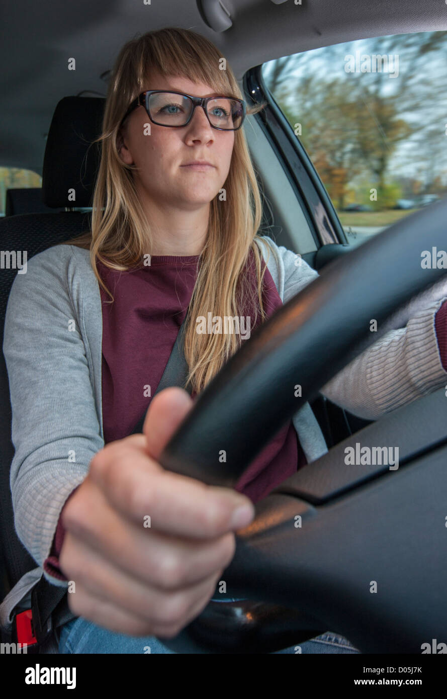 Woman is driving a car. Using a mobile phone. Not allowed while driving