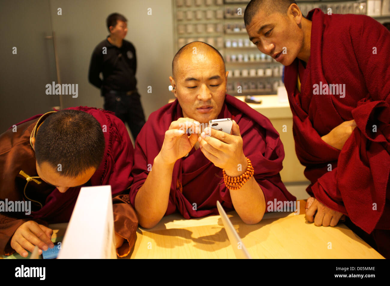 Three Tibetan lamas check iPhone in an Apple store in Wangfujing, Beijing, China.18-Nov-2012 Stock Photo