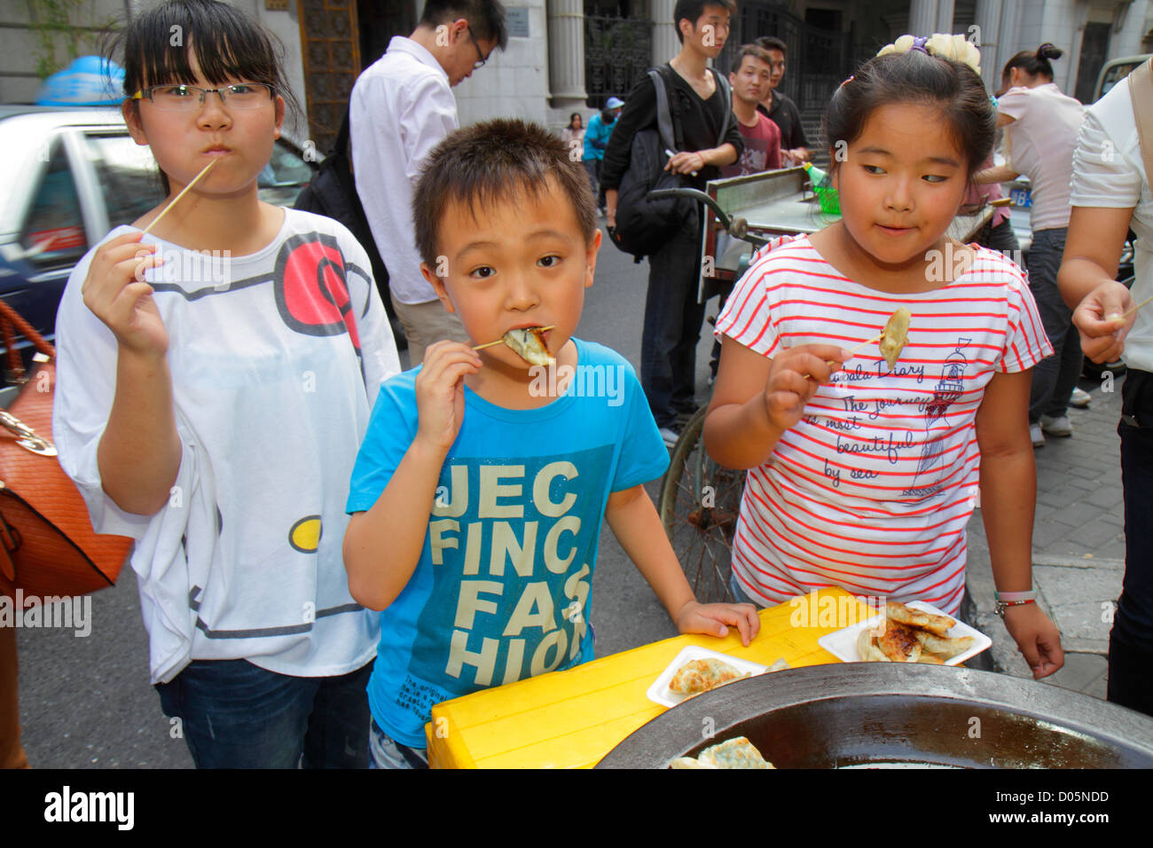 Shanghai China,Huangpu District,Dianchi Road,Asian boy boys,male kid kids child children youngster,girl girls,female,dumplings,eating,food,street,vend Stock Photo