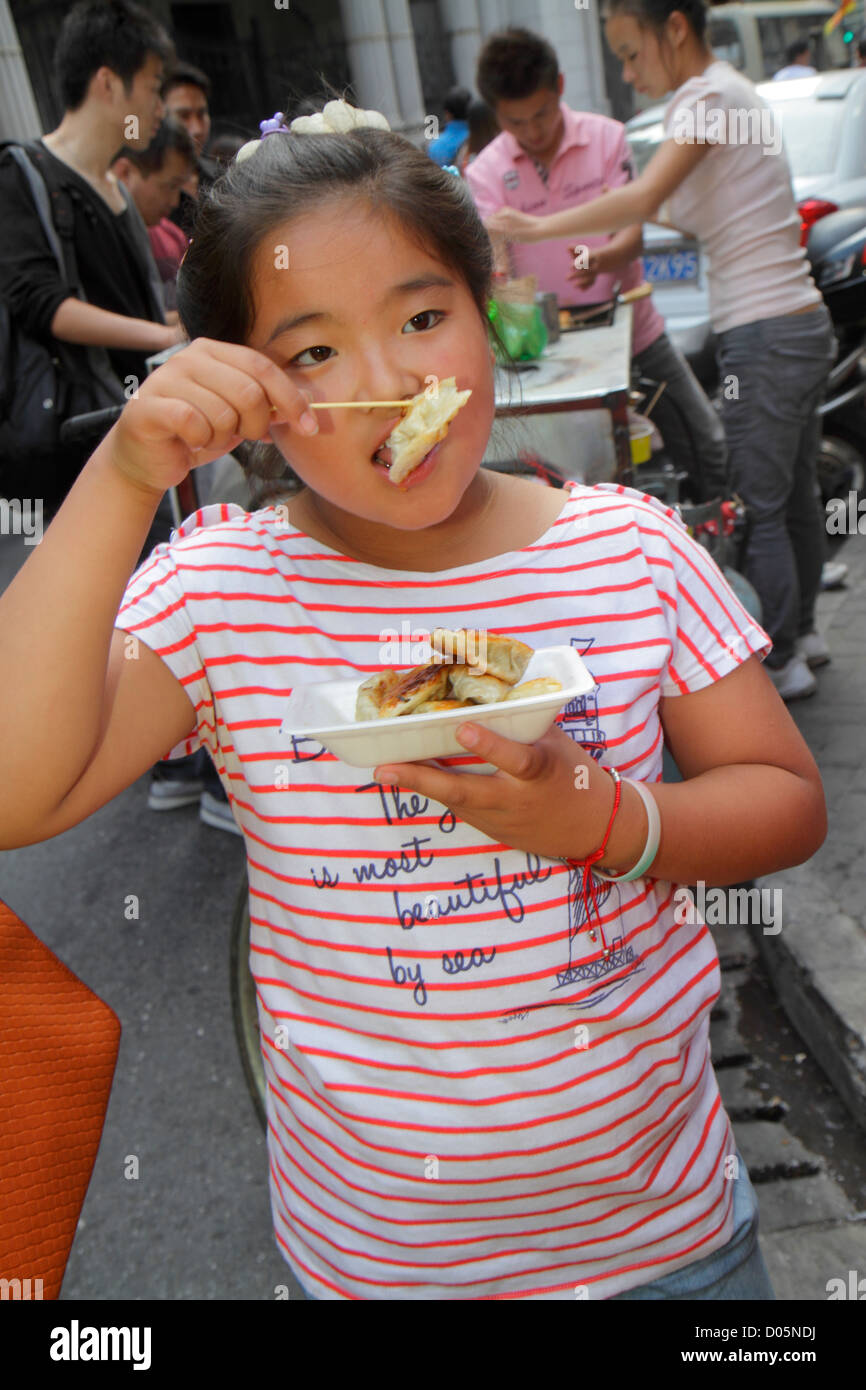 Shanghai China,Chinese Huangpu District,Dianchi Road,Asian girl girls,youngster,female kids children dumplings,eating,food,street,vendor vendors stall Stock Photo