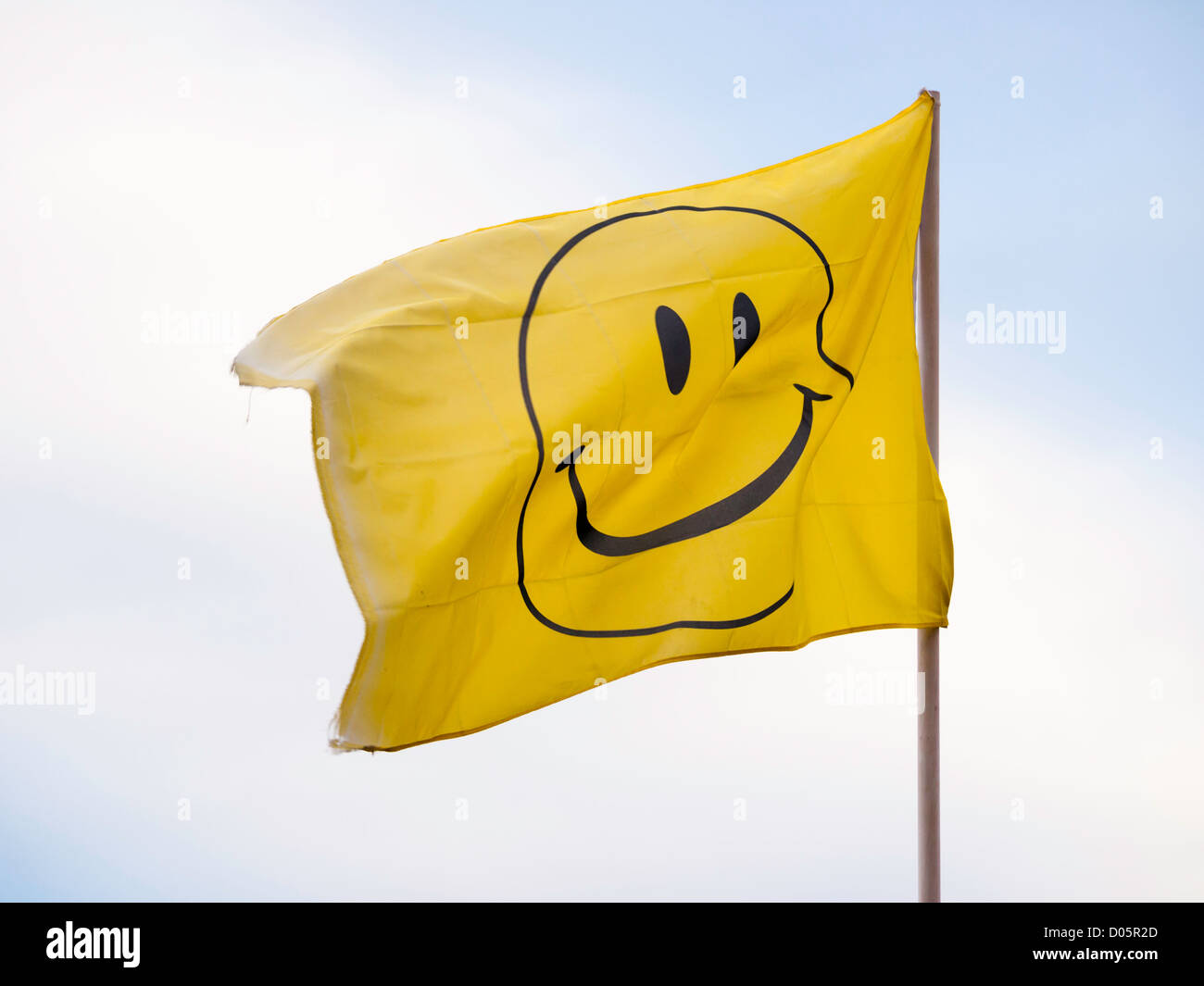 Yellow flag with a black smiley face Stock Photo