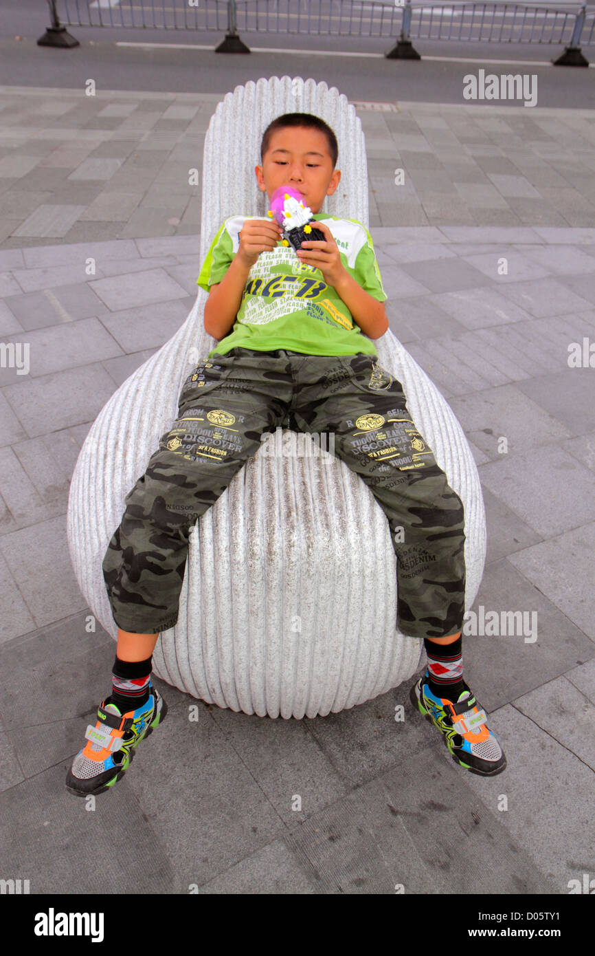 Shanghai China,Chinese Luwan District,Xintiandi,Madang Road,public plaza,sculpture,chair,Asian boy boys,male kid kids child children youngster,toy,Chi Stock Photo