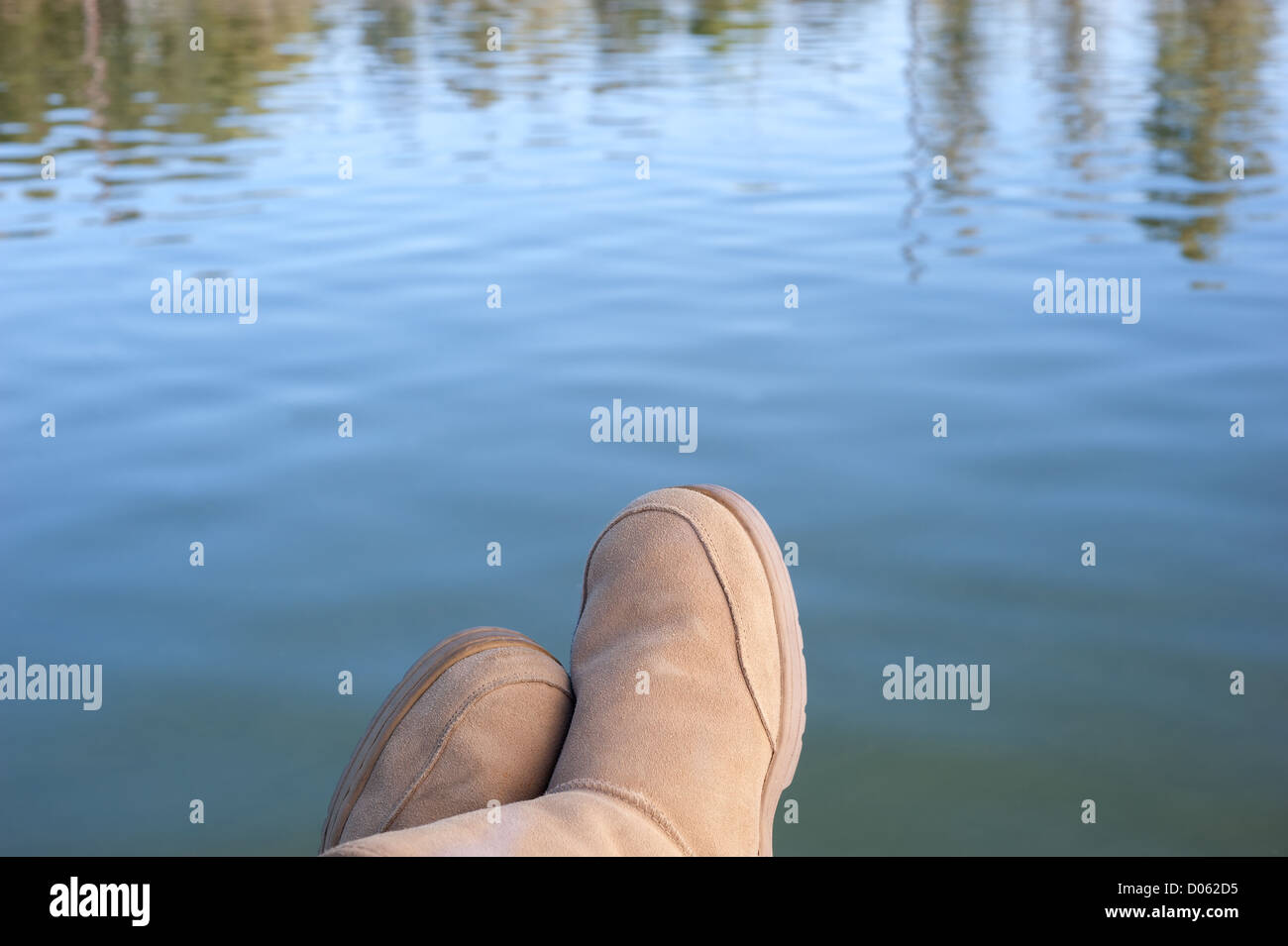 A person relaxes along the shore of a serene lake setting in the mountains during holiday. Stock Photo