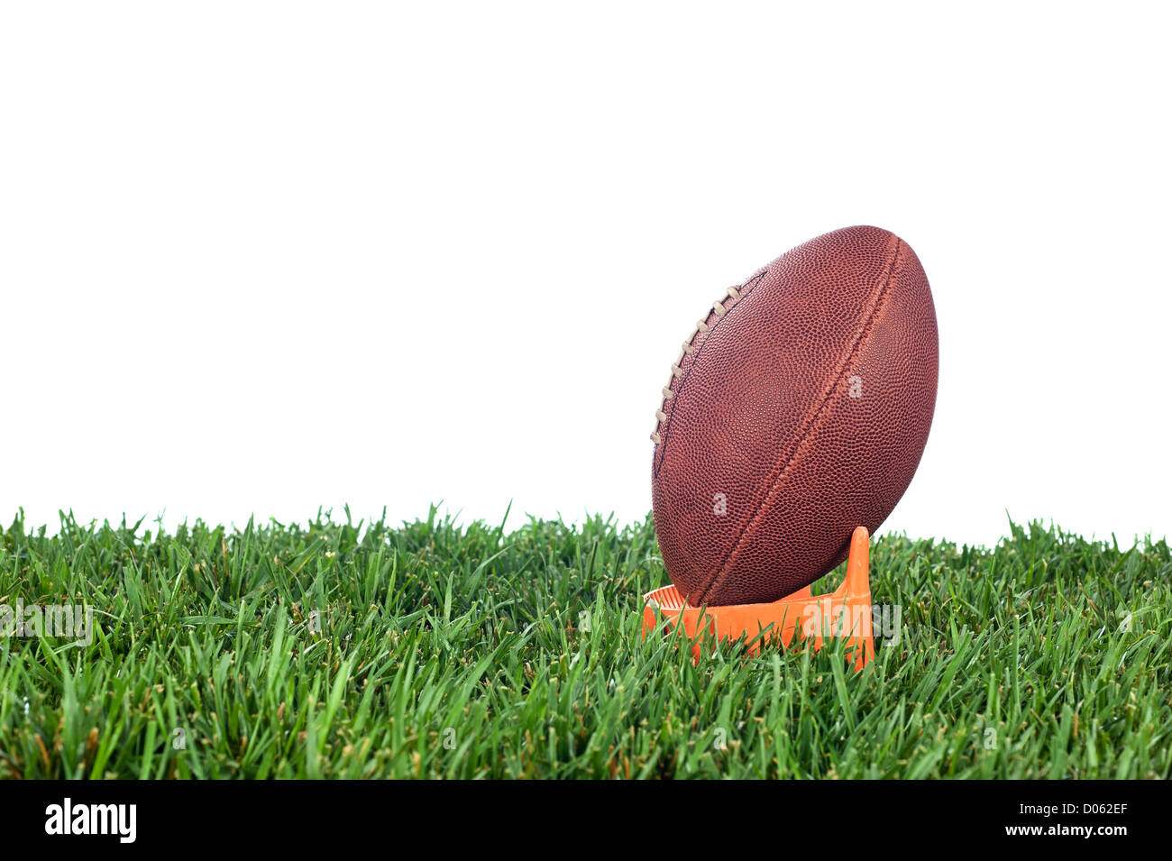 Football tee on green grass waiting for a kick off. White background for placement of copy. Stock Photo