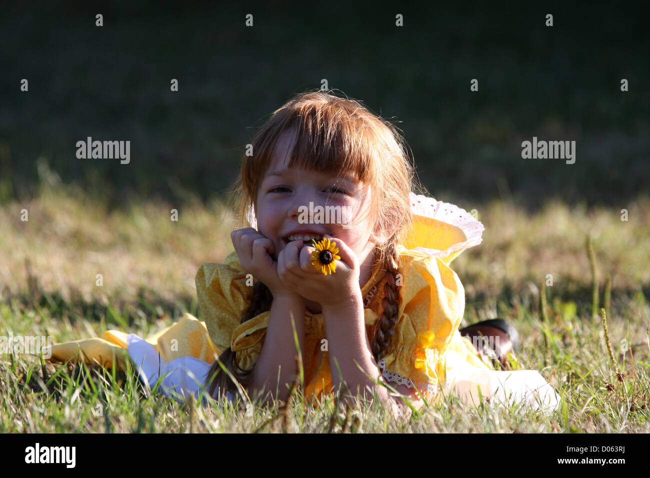 A young smiling girl holding a flower Stock Photo - Alamy